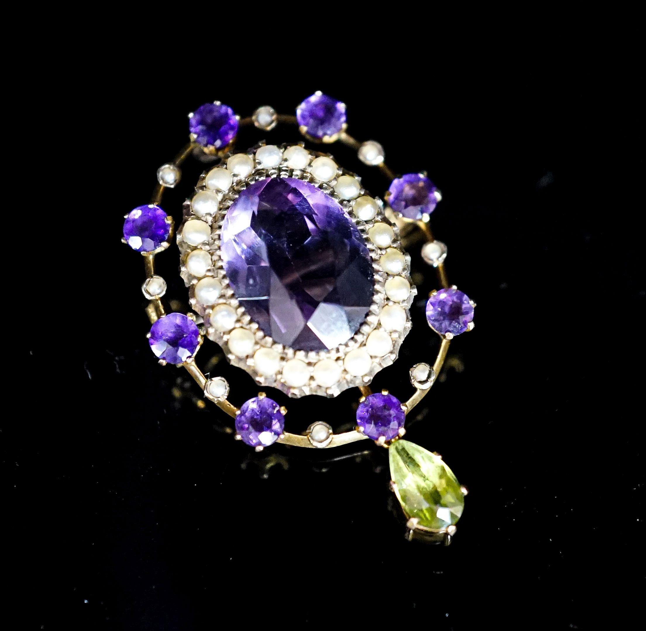 An early 20th century yellow metal, amethyst and peridot set drop oval brooch, in the suffragette colours, 35mm, gross weight 4. 6 grams.